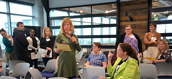 group of audience members with one woman speaking on a mic