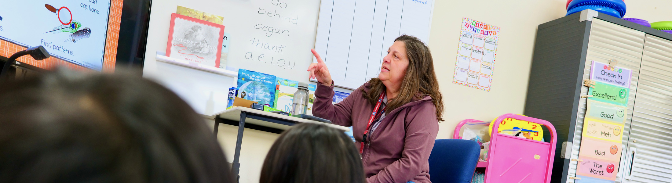 Teacher pointing up at diagrams on the wall