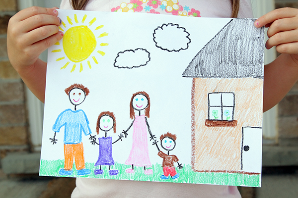 Child holding drawing of house